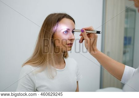 Neurologist Doctor Checking Pupillary Response To Light With Flashlight