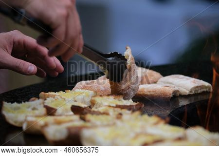 Close-up Detail View Of Chef Flipping Sandwiches Grilled At Round Steel Iron Firepit Hearth Table Su