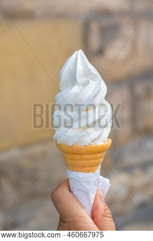 Soft Whipped Vanilla Ice Cream With Chocolate Stick In Waffle Cone In Hands