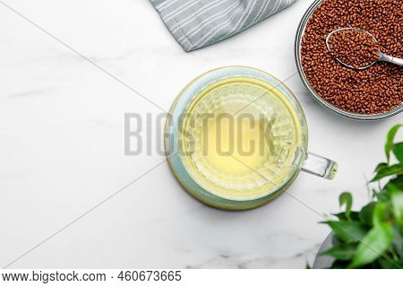 Cup Of Buckwheat Tea And Granules On White Marble Table, Flat Lay. Space For Text