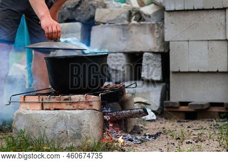 Defocus Man Cooking Fish Soup In The Iron Bowler Over A Campfire. Fish Soup Boils In Cauldron. Soup 