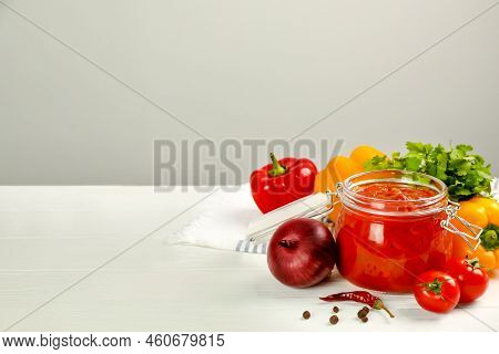 Glass Jar Of Delicious Canned Lecho And Fresh Ingredients On White Wooden Table. Space For Text