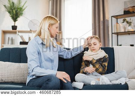 Pleasant 40-aged Caucasian Mother Measuring Temperature Of Her Teen Boy, Which Is Sitting Near Her O