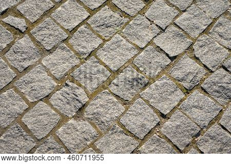 Chipped Stone Pavement Background Texture, Cobbled Street In Sunlight.