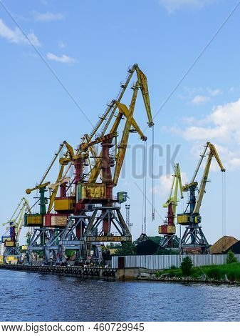 Harbor Pier With Many Cranes And Stacks Of Bulk Cargo, Coal And Wood Chips