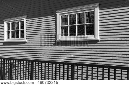 Two Vintage Identical Single Hung Windows On A Gray Colour Exterior Wall. The Windows With White Tri