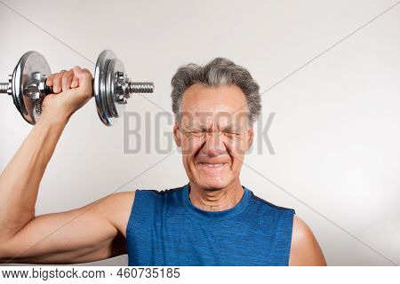 Mature Man 60plus Working Out With Weights At Home Doing Shoulder Press With One Arm
