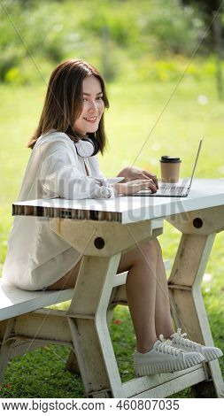 Thoughtful smile woman in park using smart digital tablet, Portrait of a young charming business wom
