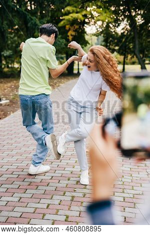 Blurred Image Of A Phone Filming A Boy And A Girl Trying To Do A Heavy Move With Their Hands And Fee