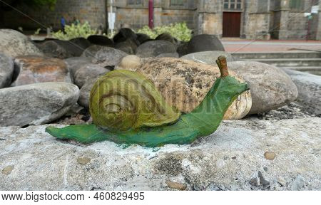 Uelsen, Germany - Aug 15 2022 Cute Painted Green Snail. This Snail Is Part Of A Statue At A Fountain