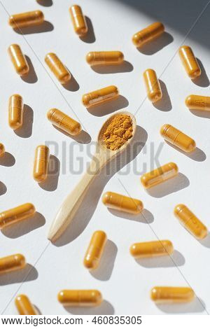 Turmeric Plus Black Pepper Extract Gelatin Capsule Close Up With Wooden Spoon. Herbal Supplement Org