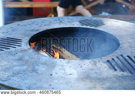 A Close-up Of The Round Frying Surface With Burning Wood Inside