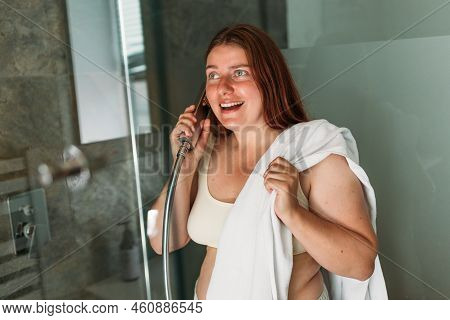 Cheerful Cute Young Woman Joking Using Shower In Bathtub In Bathroom. Attractive Gill Standing In Ba