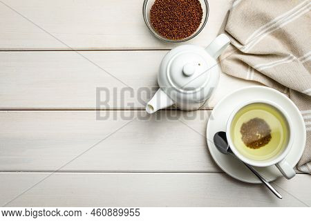 Cup Of Buckwheat Tea, Teapot And Granules On White Wooden Table, Flat Lay. Space For Text