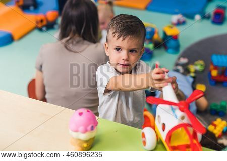 Nursery School. Toddlers On The Floor Playing With Different Plastic Toys Such As Building Blocks An