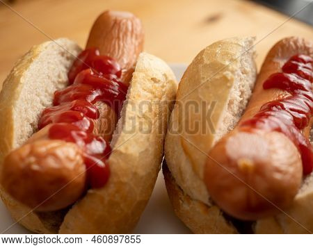 Boiled Sausage With A Bun On A Wooden Background.
