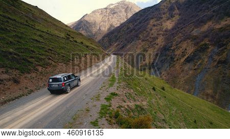 High Angle Outdoor Shot Of An Off-road Car On A Dirt Road Drving Through Mountains In A Beautiful Sc
