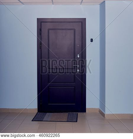 Dark Brown Door In The Entrance Of An Apartment Building With Blue Corridor Walls