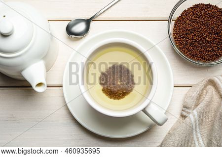 Cup Of Buckwheat Tea, Granules And Teapot On White Wooden Table, Flat Lay