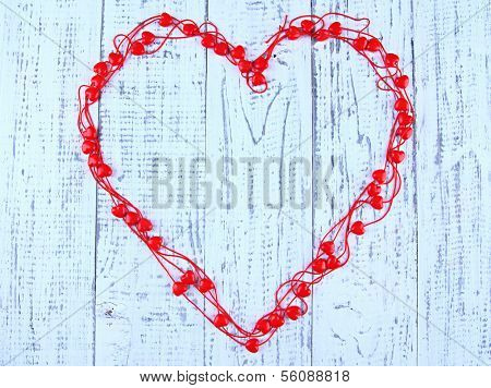 Heart-shaped beads on string on wooden background