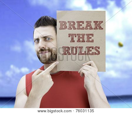 Man holding a card with the text Break The Rules on a beach background
