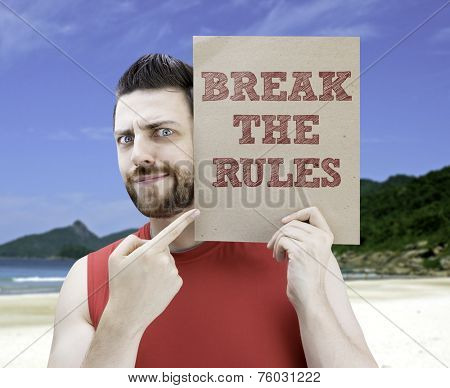 Man holding a card with the text Break The Rules on a beach background