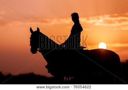Silhouette of a girl riding a horse rider on the background of the rising sun