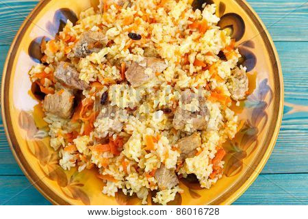Oriental pilaf, rice with meat and carrot on yellow plate