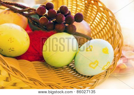 Easter eggs in a basket with a branch in the morning