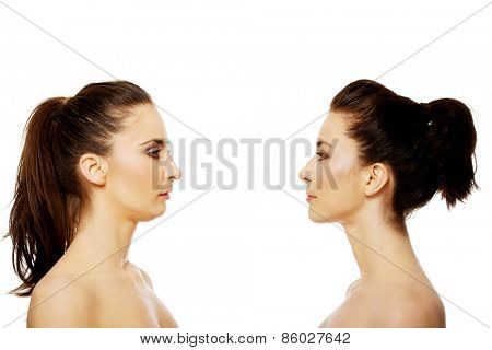 Two attractive sisters standing face to face.