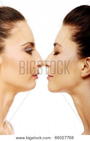 Two attractive sisters standing face to face.