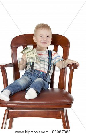 Boy sitting in chair and holding dollars
