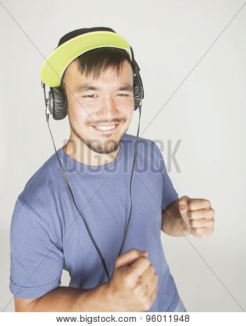 young asian man in hat and headphones listening music on white background