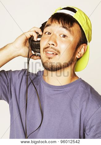 young asian man in hat and headphones listening music on white background