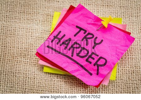 try harder - motivation words on a  purple sticky note against burlap canvas