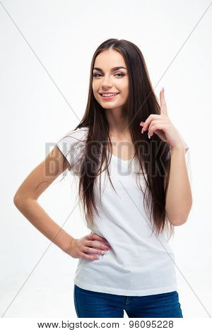 Happy young girl pointing finger up isolated on a white background. Looking at camera