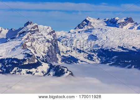 Summits of the Swiss Alps rising from sea of fog - wintertime view from Fronalpstock mountain in the Swiss canton of Schwyz.
