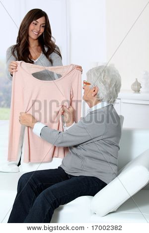 젊은 여성이 할머니에 게 새 옷을 보여주는