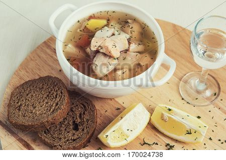 Russian traditional fish soup - ukha, served with bread lemon tomato and vodka