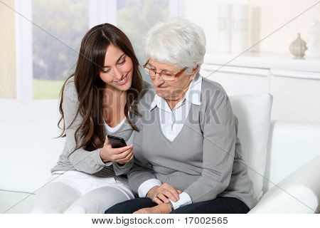 젊은 여성이 할머니에 게 휴대 전화를 사용 하는 방법을 보여주는