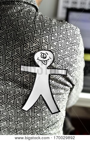 young man with a paper man in his back for the dia de los inocentes, the innocents day, a feast held in spain, hispanic america and philippines equivalent to april fools day