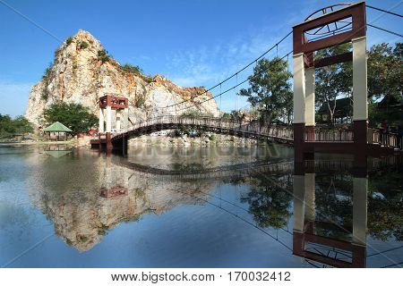 Suspension bridge across lake in central valleys from after mining and reflected image at Khao Ngoo Rock Park Ratchaburi Thailand