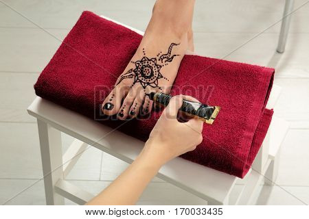 Woman applying henna on female foot