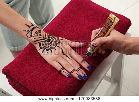 Woman applying henna on female hand
