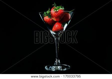 strawberry in glass on black background isolated