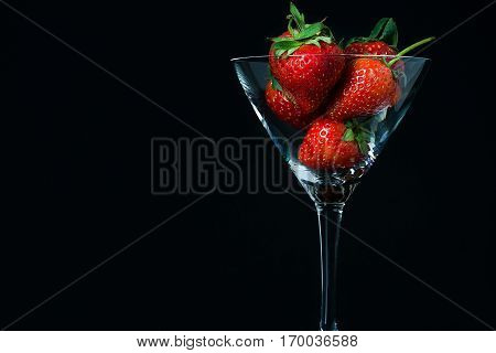 strawberry in glass on black background isolated