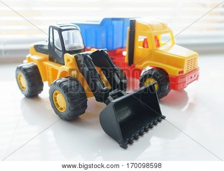 Toy Wheel Loader and Toy Dump Truck Close up, Toy Industrial Vehicle, Plastic Wheel Loader Excavator for Earth Moving Works at Construction Site, Miniature Earth Mover, Backhoe Loader