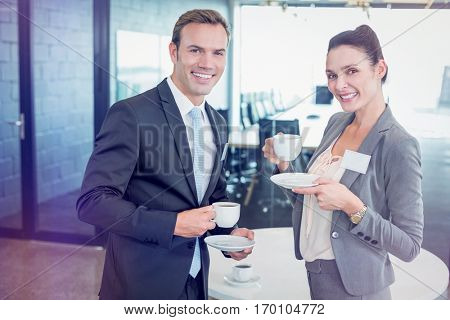 Portrait of businessman and businesswoman having tea during breaktime in office