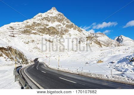 Mountain road in a sunny winter day (Swiss alps). Julier Pass, Graubunden, Switzerland.  Julier Pass - mountain pass in Switzerland, in the Albula Range of the Alps.