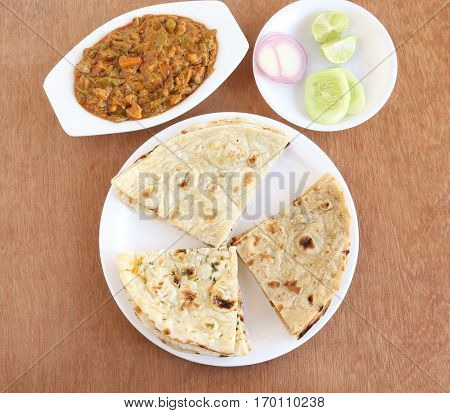 Indian food, naan, roti and kulcha, three of the types of traditional and popular Indian bread, and vegetable curry and salad.